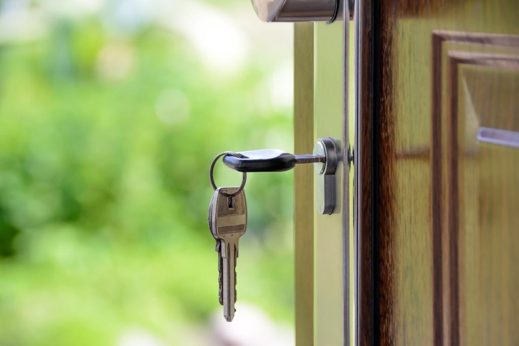 Key inserted in door lock against a blurred green background, symbolizing security and real estate.